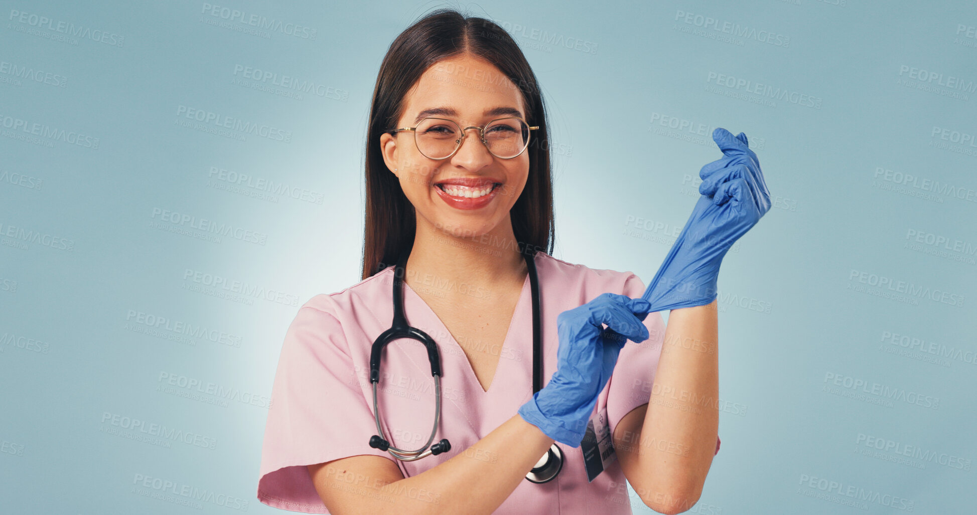 Buy stock photo Gloves, woman and nurse in studio for healthcare, prepare and cancer care on blue background. Happy person, medical and oncology worker with ppe for safety, protection and getting ready with portrait