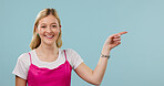 Happy, pointing and fashion with portrait of woman in studio for announcement, retail news and space. Sale promotion, style advertising and mockup with female person on blue background for offer