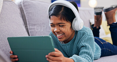 Buy stock photo Streaming, headphones or girl in home with tablet, cartoon series or online game on weekend break. Happy, multimedia or child on sofa with tech, comedy entertainment or playing in digital competition