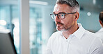 Business, man and reading on computer in office for insurance auditing, finance news and research. Serious, mature financial advisor and tech for monitoring trends, CRM update and wealth management