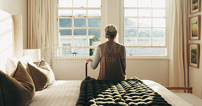 Buy stock photo Thinking, window and back of senior woman in bedroom for nostalgia, remember or reflection. Walking stick, ideas and elderly person in retirement on bed for relax, memory or planning for day in house