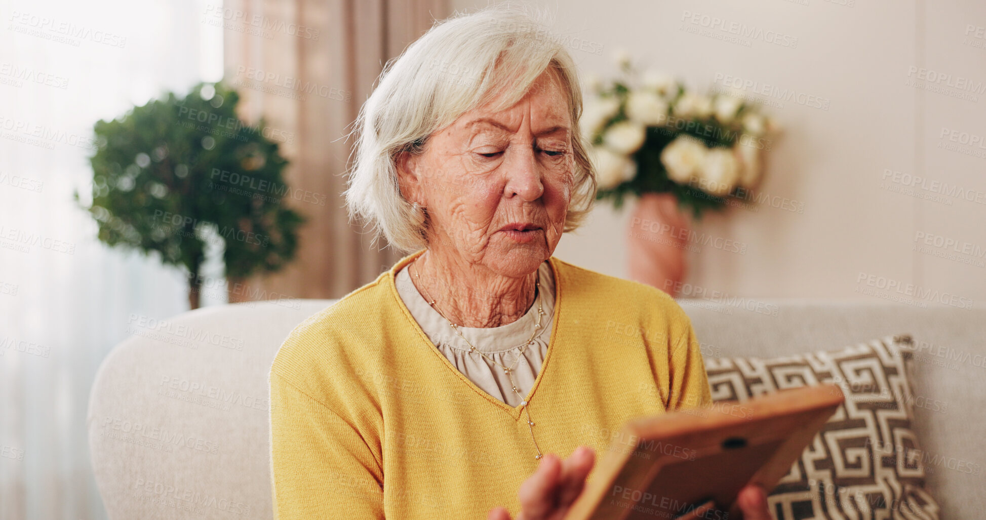Buy stock photo Sad, old woman and memory at house with picture frame, remembrance and nostalgia for loneliness. Grief, sentimental and senior person in lounge with photo album, reminiscing moment and mourning loss