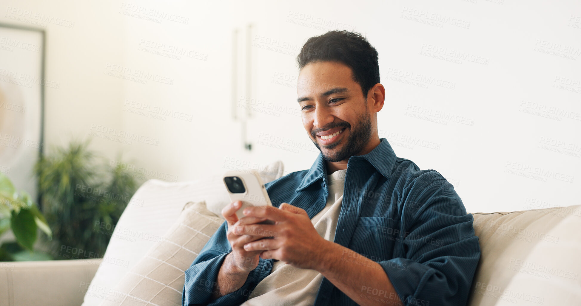Buy stock photo Texting, connection and man on sofa with phone, online chat and post reaction on social media app. Space, happy and person in house with tech, message update and communication on digital platform.