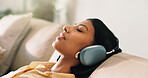 Headphones, relax and woman on sofa in home listening to music, playlist and album on app. Calm, audio tech and person streaming online radio, track or song for break in living room at house.