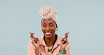 Hope, happy and black woman in studio with fingers crossed, wink and positive mindset for future. Space, female person smile and good luck emoji with wish, optimism and waiting on blue background.