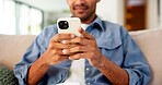 Phone, hands and man on sofa in home for texting, email or social media on mobile app in living room. Technology, typing and person on cellphone for chatting online with weekend relax in house.