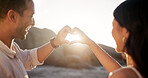 Couple, beach and heart hands with smile for travel, romance and outdoor with bonding, memory and holiday. Love, sunset and tropical vacation and summer with gesture for partner, nature or commitment