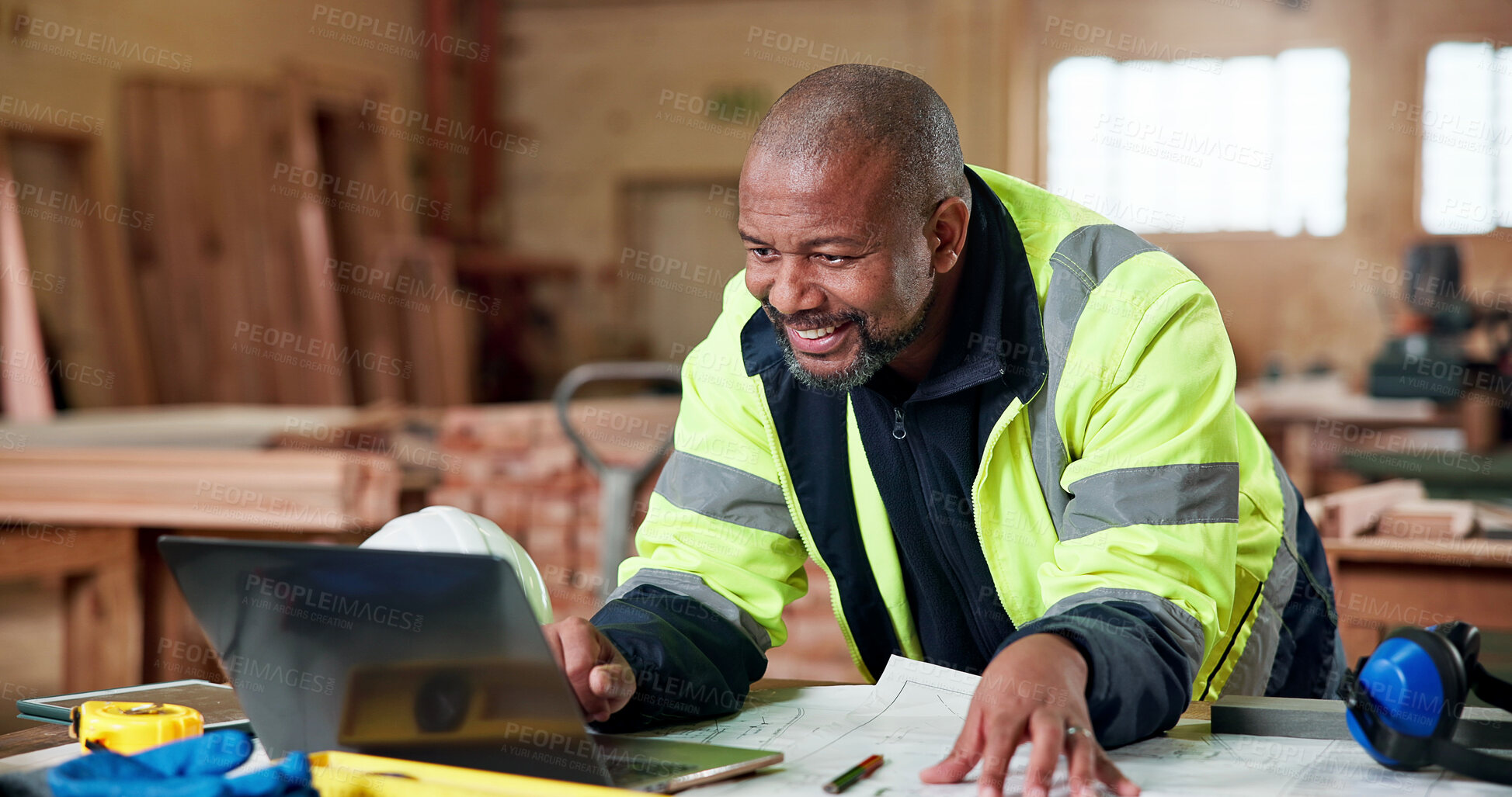 Buy stock photo Construction, laptop and smile with black man in carpentry workshop for lumber or timber supply. Computer, happy and review with mature carpenter in woodworking factory for online building order