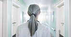 Back, doctor and walking in hospital for healthcare, punctual person and wellness service. Mature woman, clinic hallway and arrival of professional clinician, medical duty or shift at corridor
