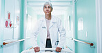 Walking, woman and doctor with bed in hospital for ICU, operation or ER healthcare in corridor. Support, serious and mature surgeon with stretcher for surgery or medical service in clinic hallway.