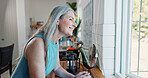 Thinking, old woman and window at house with smile, vision and daydreaming for stress relief. Happy, senior person and thoughts in kitchen with reflection, outdoor view and nostalgia memory for peace