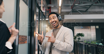 Buy stock photo Excited, pointing and smile of business man in office for financial collaboration or development. Greeting, headphones and music with happy employee in corporate workplace corridor for arrival at job
