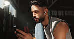 Man, earphones and phone in gym for fitness, check wellness app or health stats with connection. Person, audio and technology for tracking exercise goals, sports podcast and internet with training