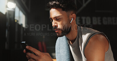 Buy stock photo Man, earphones and phone in gym for fitness, check wellness app or health stats with connection. Person, audio and technology for tracking exercise goals, sports podcast and internet with training