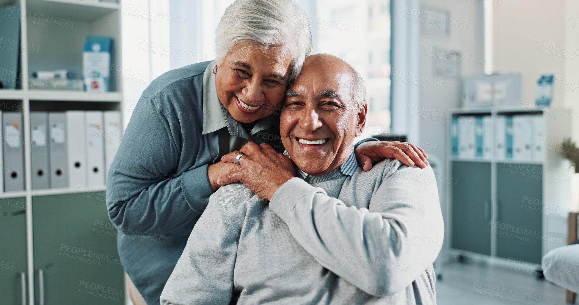 Buy stock photo Portrait, old couple and hug in hospital for healthcare checkup, patient and support for care. Happy man, woman and holding hands for medical aid, retirement partner and geriatric health service