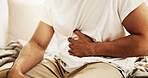 Man, hands and sick in home with stomach ache, allergy or constipation from irritable bowel syndrome. Person, abdomen pain and cramps in house with indigestion, disease and gas from bloating problem.