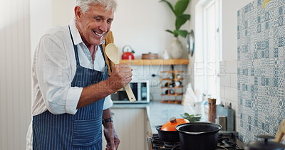 Buy stock photo Singing, happy and senior man with cooking in kitchen at house with music, radio or album on weekend. Spoon, karaoke and elderly person listening to online playlist for preparing dinner in apartment.