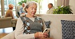 Phone, typing and senior woman in retirement home with texting, email or reading blog on mobile app. Tech, relax and elderly person with cellphone for chatting on website in living room at house.