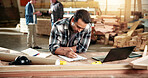 Man, carpenter and writing at warehouse with clipboard, stock and timber price for production. Person, laptop and checklist at workshop for carpentry, quotation and order for manufacturing furniture