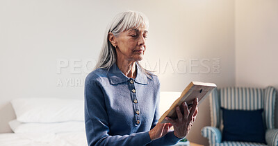 Buy stock photo Thinking, photo frame elderly woman in home with memories, nostalgia and lonely in retirement. Senior widow, reflection and picture in bedroom for reminder, broken heart and looking at souvenir
