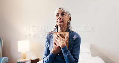 Buy stock photo Thinking, photo frame senior woman in home with memories, nostalgia and lonely in retirement. Elderly widow, reflection and picture in bedroom for reminder, broken heart and hug with souvenir