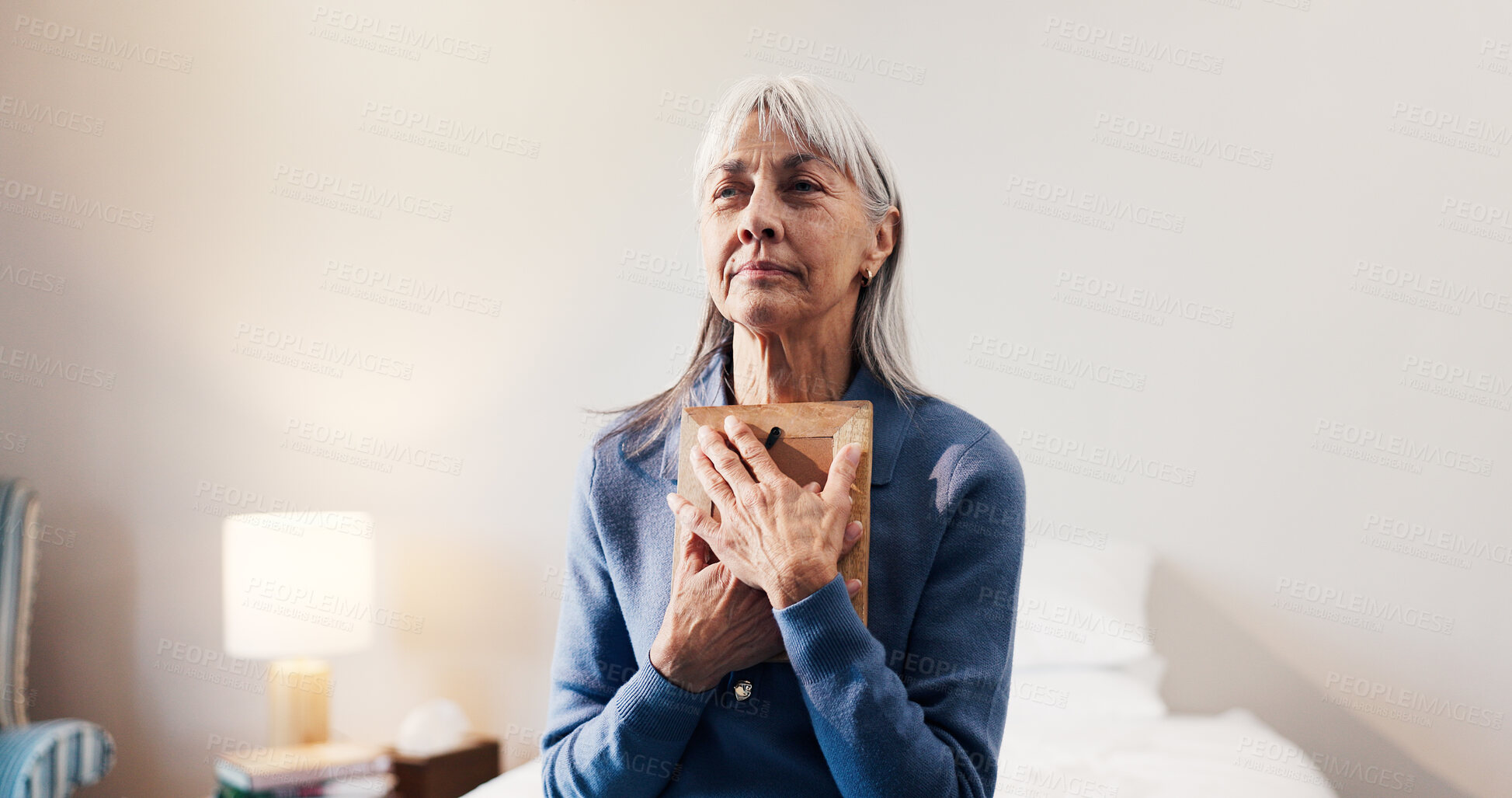 Buy stock photo Thinking, photo frame senior woman in home with memories, nostalgia and lonely in retirement. Elderly widow, reflection and picture in bedroom for reminder, broken heart and hug with souvenir