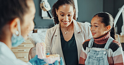 Buy stock photo Child, dentist and mother in practice with model, teaching or instructions for dental care. Orthodontist, family and typodont in office for visual learning, teeth wellness or girl patient for checkup