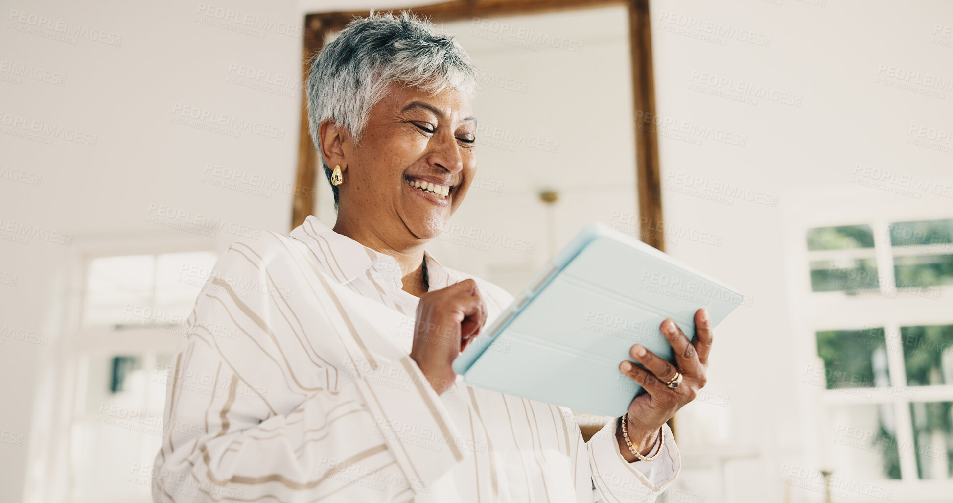 Buy stock photo Mature, woman and smile in living room with tablet, browsing website and watch social media video. Happy, person and online application in home with digital tech, internet connection and wellness.
