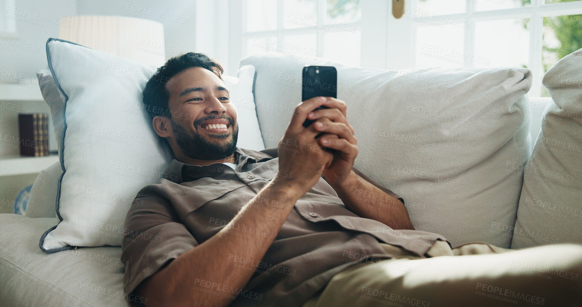 Buy stock photo Texting, smile and man on couch with phone, online communication and social media scroll on day off. Digital, happy and person in home with tech, message notification and chatting on weekend break.