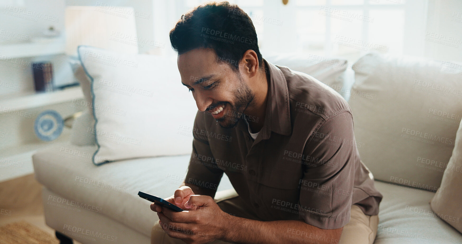 Buy stock photo Texting, happy and man on couch with phone, online communication and social media scroll on day off. Reading, smile and person in house with tech, message notification and chatting on weekend break.