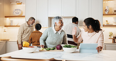 Buy stock photo Women, cooking and big family in kitchen with tablet, meal prep and prepare food for bonding in home. Generations, happy people and tech for online recipe, conversation and laughing for holiday