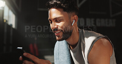 Buy stock photo Man, smile and phone in gym with earphones, browsing fitness app and listen to online music playlist. Happy, person and exercise break in health club with audio tech, streaming radio or social media.