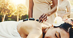 Spa, woman and hot stones on back for stress relief, massage and deep tissue treatment for healing. Hospitality, resort and person with heat therapy for pamper, self care and relax for zen wellness