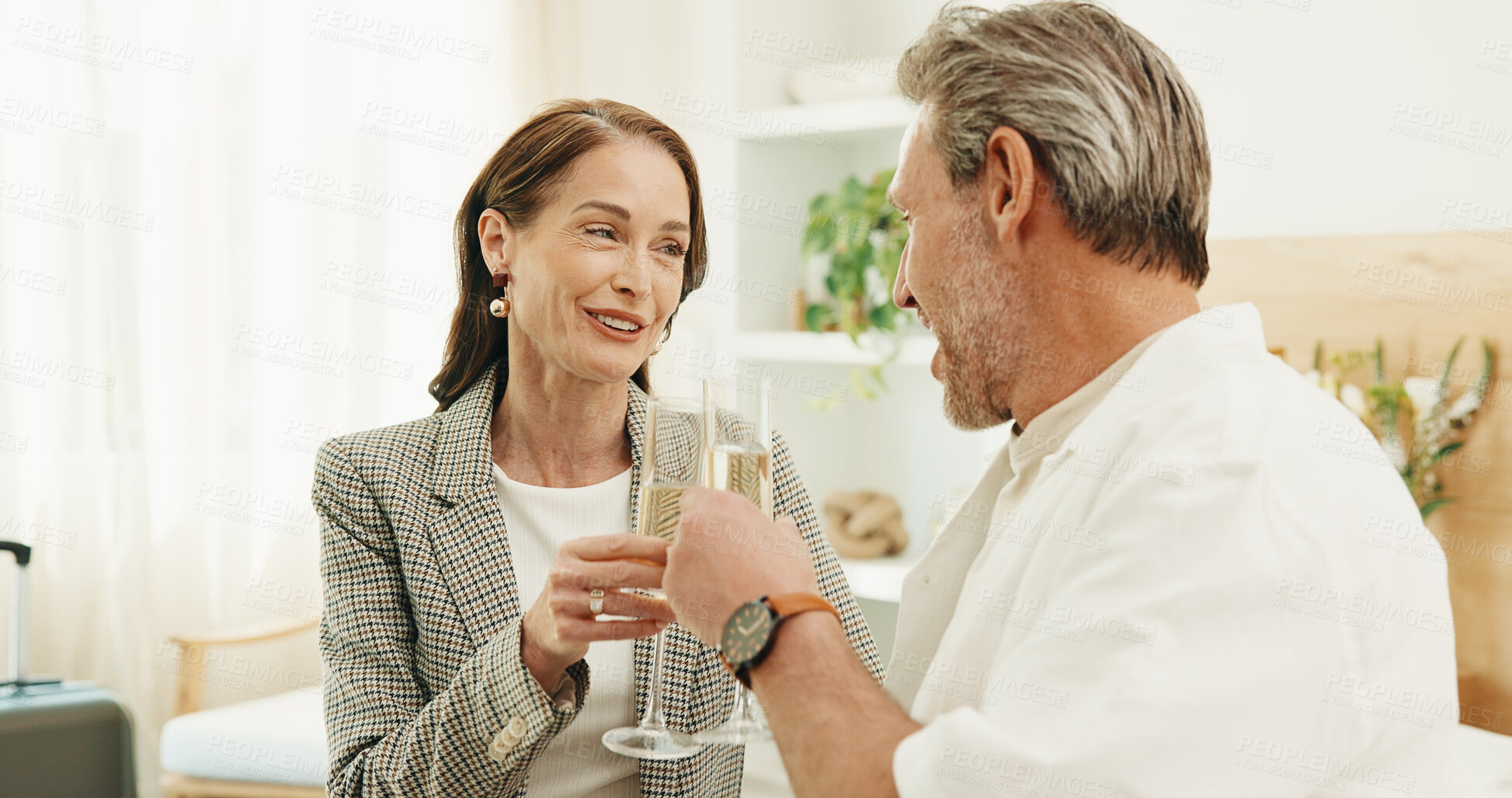 Buy stock photo Couple, travel and smile with champagne in hotel, laughing and celebration with partner or together. Relationship, commitment and happy mature people with alcohol, toast and anniversary in motel