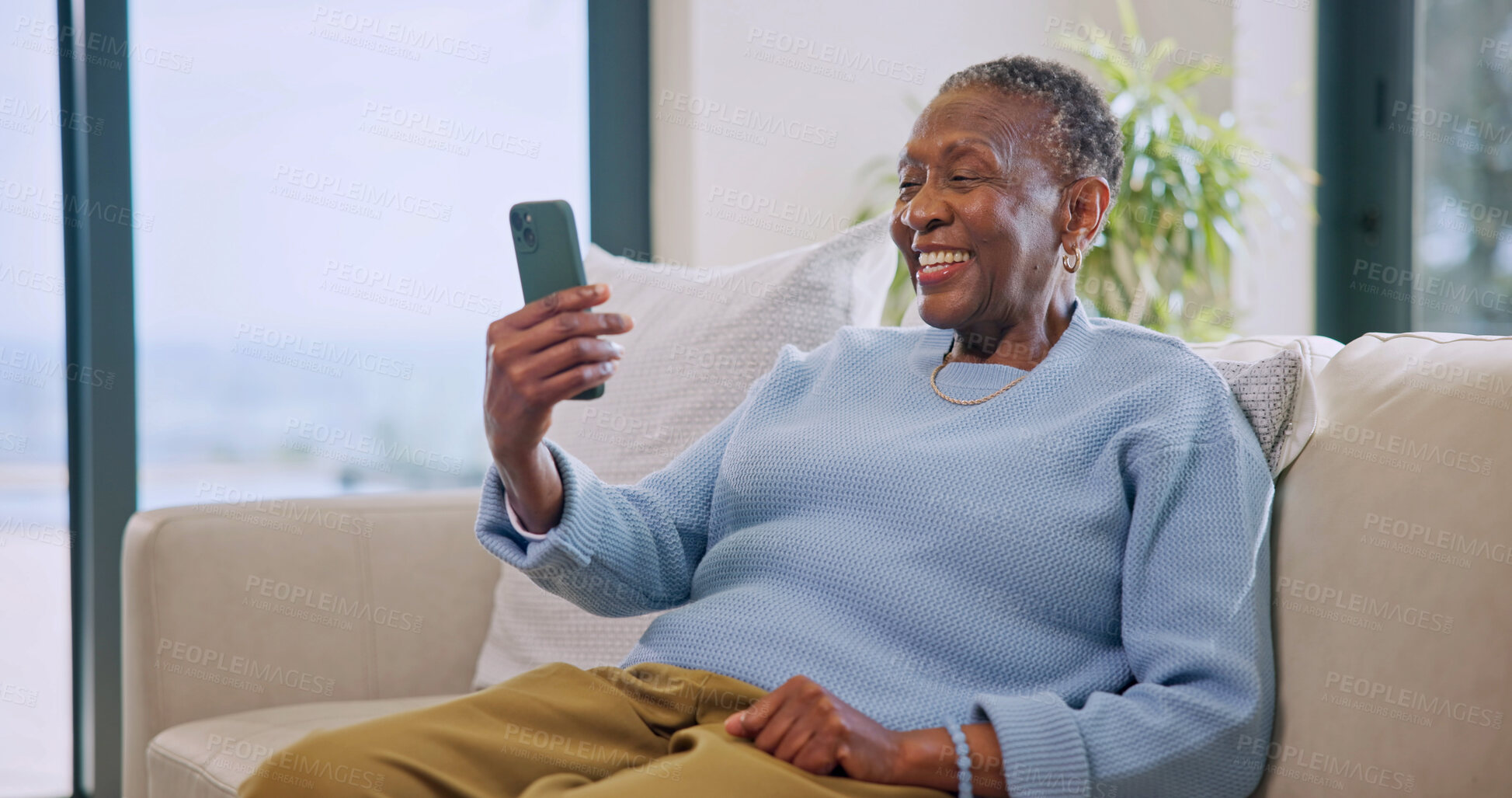 Buy stock photo Video call, gossip and old woman with phone in lounge, laugh and communication with contact on web. Retirement, home and senior black person with mobile, happiness and virtual chat with social media