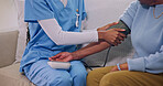 Caregiver, hands and patient in nursing home with blood pressure machine for wellness check. Healthcare, monitor hypertension and person with nurse, assisted living and medical evaluation in lounge