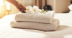 Hand, towel and flowers on hotel bed for luxury accommodation, cleanliness and hospitality service. Housekeeper, person and orchard in lodge with fresh linen, hygiene and peace for resort vacation.