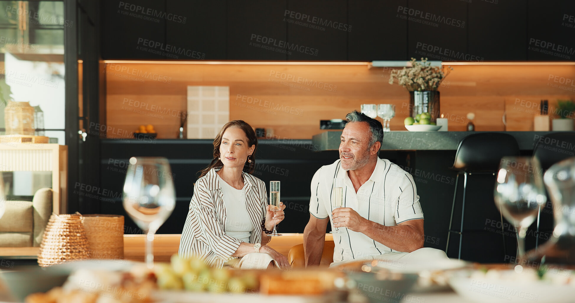 Buy stock photo Couple, home and smile with champagne, relax and bonding with partner in lounge or thinking together. Relationship, anniversary and happy mature people with alcohol, reflection and love in house