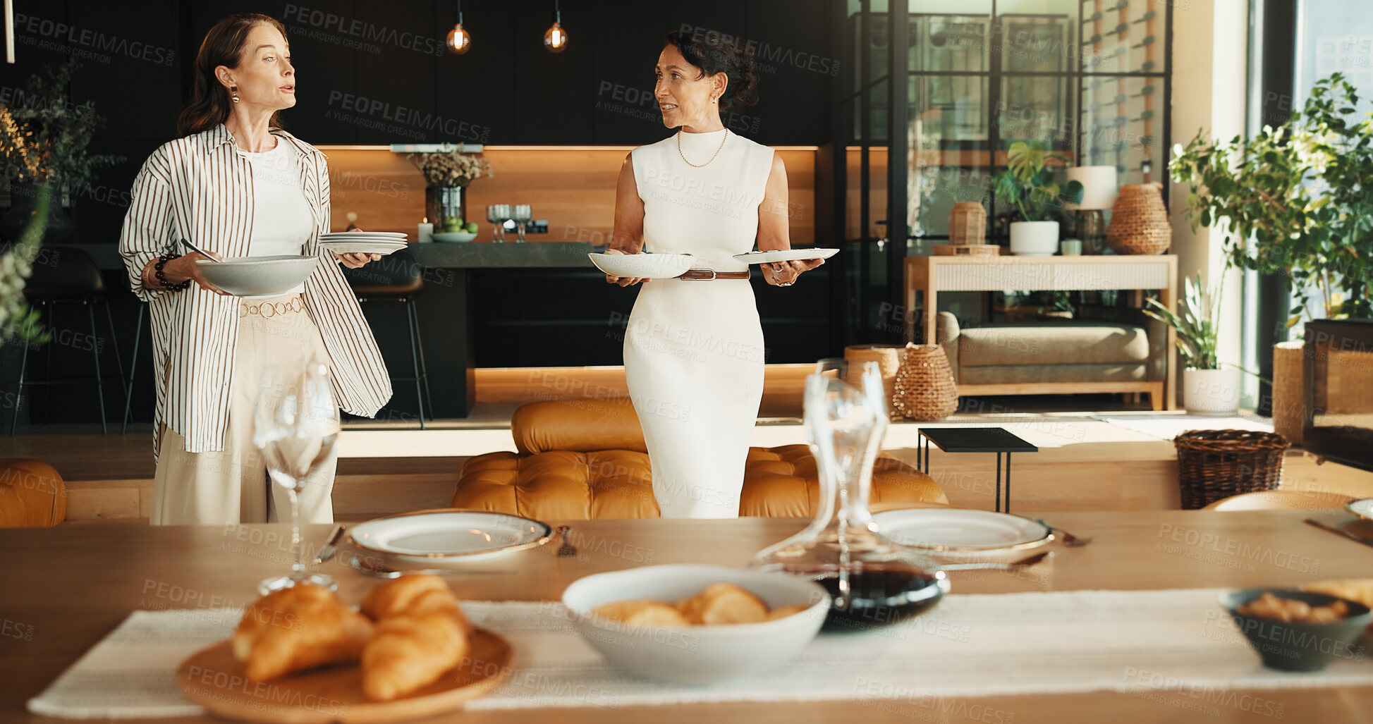 Buy stock photo Friends, host and help with food at house for social gathering, meal or dining table setting. Mature women, happy people and together in home with planning, brunch or talking of catering for party