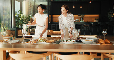 Buy stock photo Friends, host and help with food in home for social event, meal or dining table setting. Mature women, serious and together in house with healthy snack, brunch or talking dietary for party catering