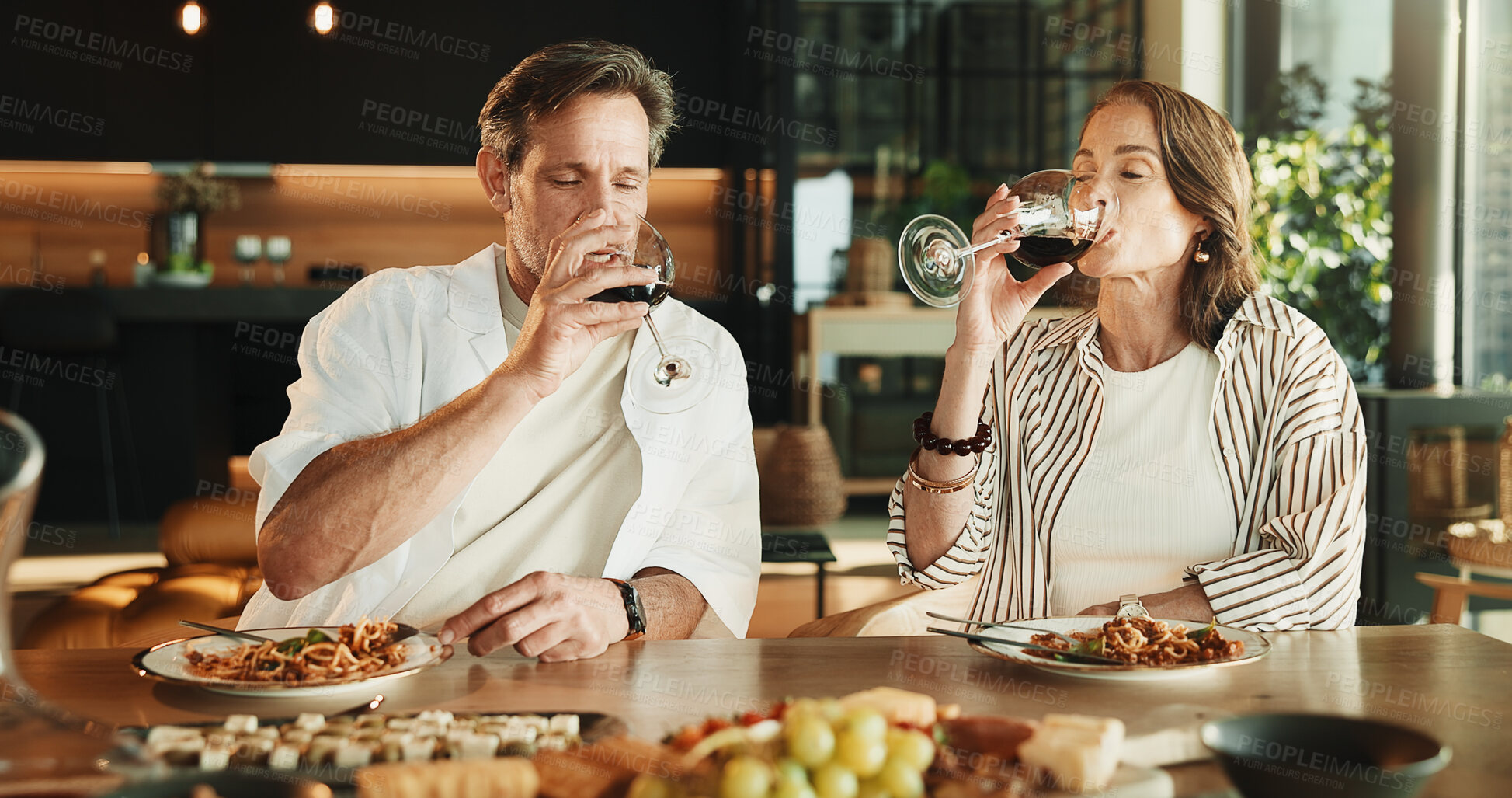 Buy stock photo Couple, food and drinking in home with wine, relationship milestone and anniversary meal at table. Woman, mature man and relax with alcohol, marriage bonding and lunch date with connection in house