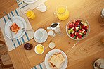 Food, table and breakfast with juice in home with health, wellness or nutrition in morning. Plate, dining room and top view of diet meal with toast, fruit salad and orange drink in apartment.