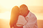 Happy, sunset and couple with hug by beach for bonding, love and care on seaside vacation. Date, summer and man embracing woman by ocean or support in marriage on holiday, weekend trip or travel.