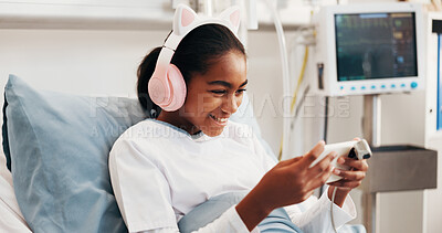 Buy stock photo Phone, headphones and kid in hospital bed with music, play online game and surgery recovery. Happy patient, mobile and girl with audio in pediatric ward for gaming, watch video or rest for healthcare