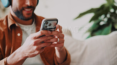 Buy stock photo Man, hands and music or phone on home sofa for streaming, podcast or online audio subscription. Smile, headphones and male person relax on couch with mobile app, technology and typing for sound