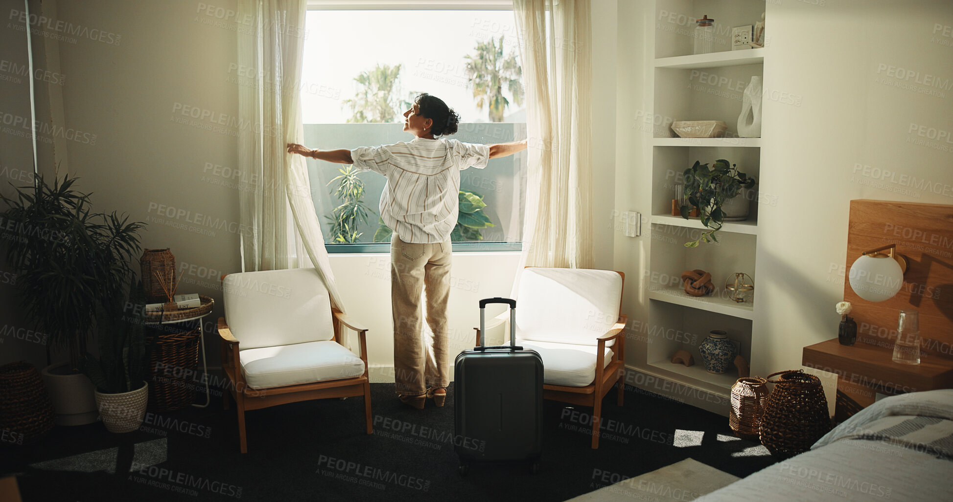 Buy stock photo Window, curtain and happy woman with suitcase in hotel for holiday getaway, travel or vacation. Back, mature person and relax with sunshine for weekend or morning stay in luxury bedroom or resort