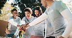 Group, volunteer and happy people with hands together in park for outdoor outreach or teamwork. Excited, community service and NGO piling with stack or smile for donation mission or charity in nature