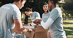 Volunteer, team and people in park with box for charity program, outreach and non profit event. Ngo, community and men with women with parcel for collection, donation and help for food drive outdoor