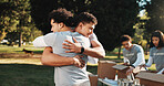 Men, hug and volunteers with donations, outdoor and bonding with friends and social responsibility. People, embrace and community service at park, happiness and collaboration for nonprofit project