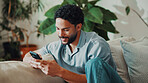 Happy, man and typing in living room with phone, social media app and entertainment on weekend break. Person, smile and relax in home with tech, text message and internet for digital communication.